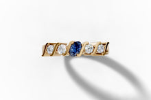 Load image into Gallery viewer, Top view of five-stone band with an oval lab-grown blue sapphire center and four round-brilliant lab diamonds set between polished S-curved bars in 14k yellow gold