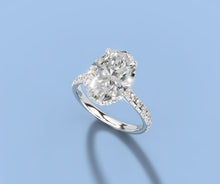 Load image into Gallery viewer, Angled view of oval lab diamond hidden halo ring showing the four claw prongs and pave shoulders in 14k white gold
