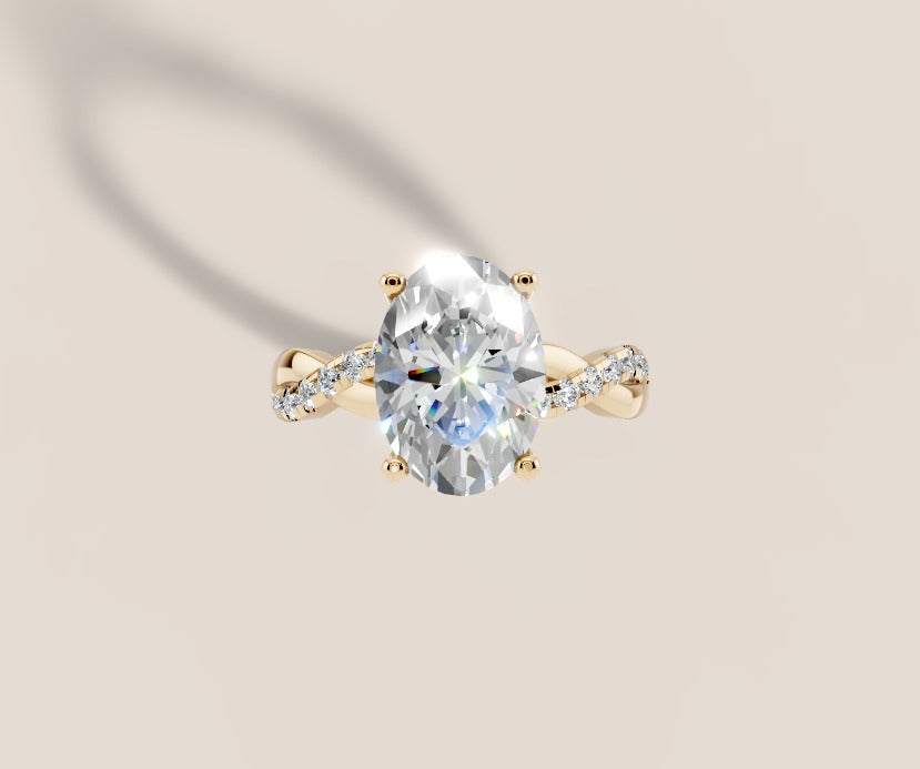 Top view of oval lab diamond engagement ring with four-prong setting and twisted pave shank in 14k yellow gold