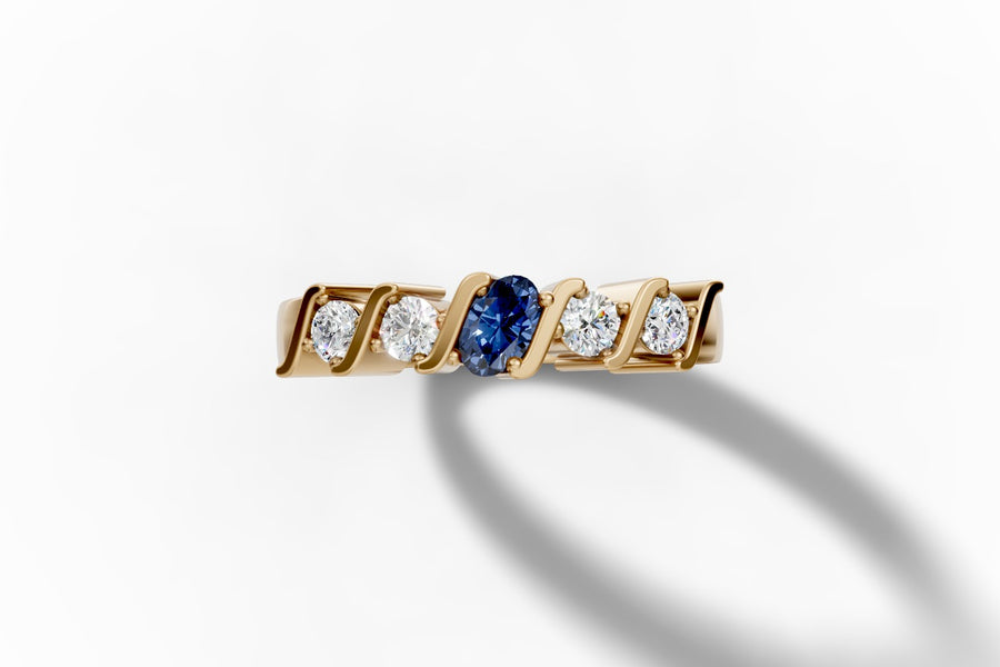Top view of five-stone band with an oval lab-grown blue sapphire center and four round-brilliant lab diamonds set between polished S-curved bars in 14k yellow gold