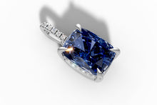 Load image into Gallery viewer, Close-up of the cushion-cut blue sapphire held in four claw prongs with round pave diamonds
