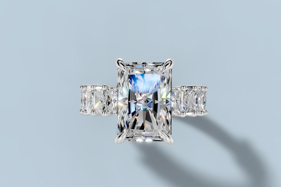 Top view of elongated radiant lab diamond engagement ring in four claw prongs with radiant-cut accents set crosswise along the band in 14k white gold