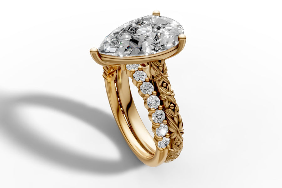 Pear-cut lab diamond ring in 14k yellow gold with round pave shoulder and carved floral band, three-quarter view