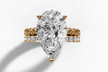 Load image into Gallery viewer, Top view of elongated pear-cut lab diamond over carved floral band and round pave row in 14k yellow gold
